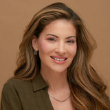Woman with long, wavy hair wearing a green top against a brown background