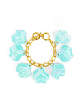 A gold-tone bracelet with teal iridescent petal charms attached to it, secured with a toggle closure.