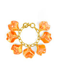 A gold-tone bracelet with orange iridescent petal charms attached to it, secured with a toggle closure.