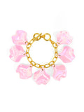 A gold-tone bracelet with pink iridescent petal charms attached to it, secured with a toggle closure.