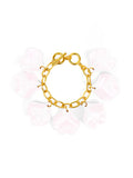A gold-tone bracelet with  white iridescent petal charms attached to it, secured with a toggle closure.