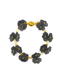 A bracelet with a black lotus flower design and a gold-colored clasp.