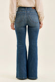 Person wearing blue flared jeans on a beige background