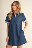 Woman wearing a blue denim dress with striped sleeves on a beige background