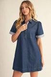 Woman wearing a denim dress with white trim on a beige background