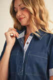 Woman wearing a blue denim shirt over a striped shirt with a neutral background