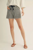 Person wearing black and white striped shorts on a plain background