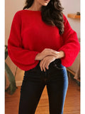 Person wearing a red sweater and black pants indoors.