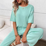 Woman wearing a mint green outfit sitting on a white couch.