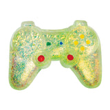 A translucent green plastic game controller filled with gold glitter and multicolored confetti, featuring red thumbsticks and yellow and blue buttons, on a white background.