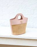 Pink and straw handbag on a white surface with a light background