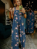 Woman taking a mirror selfie wearing a blue floral jumpsuit in a store.