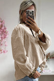 Person wearing a striped shirt with rolled-up sleeves, taking a mirror selfie.