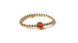 Gold bracelet with a basketball charm on a white background
