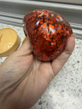 Hand holding a red glittery ball on a speckled countertop