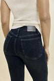 Rear view of a person wearing dark indigo skinny jeans and a cream sleeveless top, showing the back pocket and a Judy Blue brand label on the waistband.