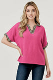 Woman wearing a pink top with leopard print accents on a white background