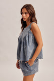 Woman wearing a denim dress with floral embroidery on a plain background