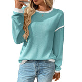 Woman wearing a teal sweater with white trim and blue jeans on a white background