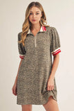 Woman wearing a patterned dress with red and white accents on a plain background
