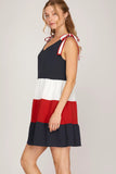 Woman wearing a black, white, and red dress with a bow detail on a light gray background