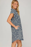 Woman wearing a denim dress with floral patterns on a gray background