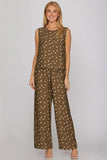 Woman wearing a brown polka dot sleeveless top and wide-leg pants on a gray background