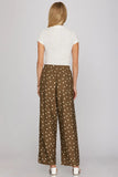 Woman wearing a white top and brown polka dot pants on a gray background