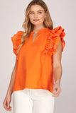 Woman wearing an orange blouse with ruffled sleeves on a light gray background