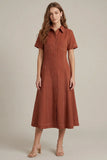 A woman modeling a rust-colored short-sleeve midi shirt dress with a button-down front, standing against a plain beige studio background.