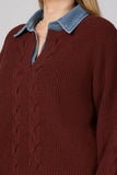 A close-up of a person wearing a burgundy ribbed knit sweater with a light blue denim shirt collar layered underneath.