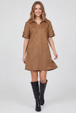 A woman modeling a brown faux-suede short-sleeve collared dress with rolled cuffs and black knee-high boots, photographed against a light gray studio background.