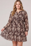 A woman modeling a long-sleeve mini dress with a brown and beige paisley pattern against a light gray studio background.