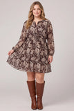 A woman modeling a brown long-sleeve mini dress with a beige paisley pattern, paired with brown knee-high boots, against a light gray studio background.