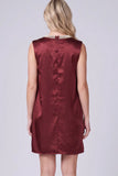 A woman viewed from the back wearing a sleeveless satin-like dress in deep burgundy with a pearl-trimmed neckline, against a light gray studio background.