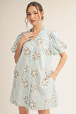Woman wearing a light blue floral dress against a plain background