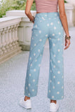 Light blue pants with white polka dots worn by a person, standing on a stone path.