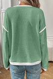 Green textured sweater with white trim worn by a person, back view.