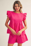 Woman wearing a bright pink dress with ruffled sleeves on a plain background