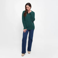 Woman wearing a green sweater and blue pants on a white background