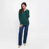 Woman wearing a green sweater and blue pants on a white background