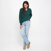 Woman wearing a green sweater and light blue jeans on a white background