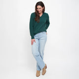 Woman wearing a green sweater and light blue jeans on a white background