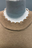 Close-up of a brown knitted sweater with a white collar on a mannequin against a gray background.