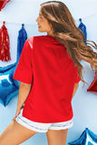 Woman wearing a red shirt and white shorts standing against a blue wall with colorful balloons.