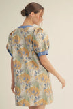 Woman wearing a floral dress with blue accents on a beige background