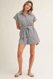 Woman wearing a black and white striped romper on a plain background