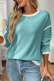 Woman wearing a teal sweater with white trim in a home setting