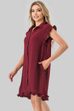 A woman modeling a sleeveless burgundy button-front nightgown with ruffled shoulder and hem details, photographed against a solid light gray studio background.