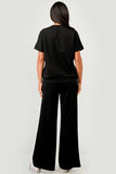 Person wearing a black t-shirt and wide-leg pants on a white background